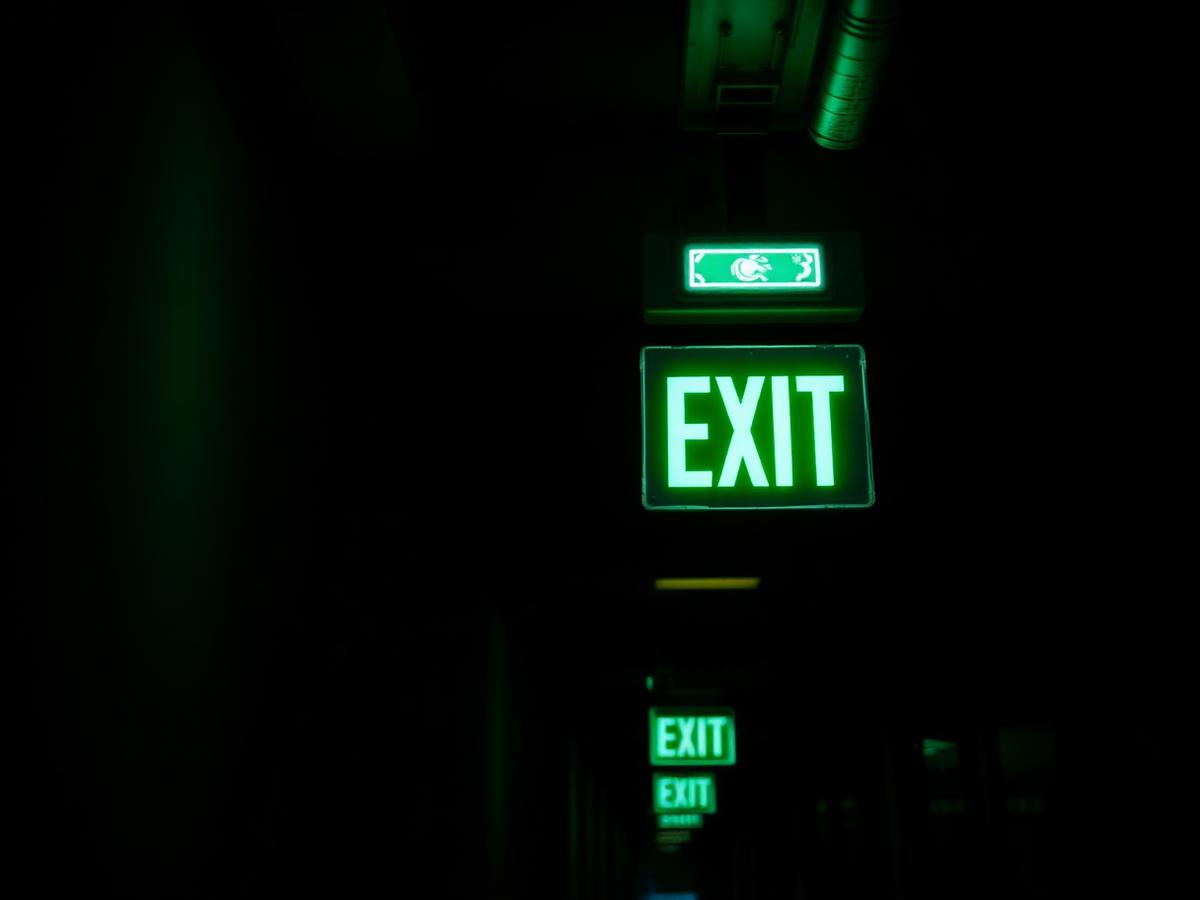 Illuminated emergency exit sign and emergency luminaire in a dark corridor